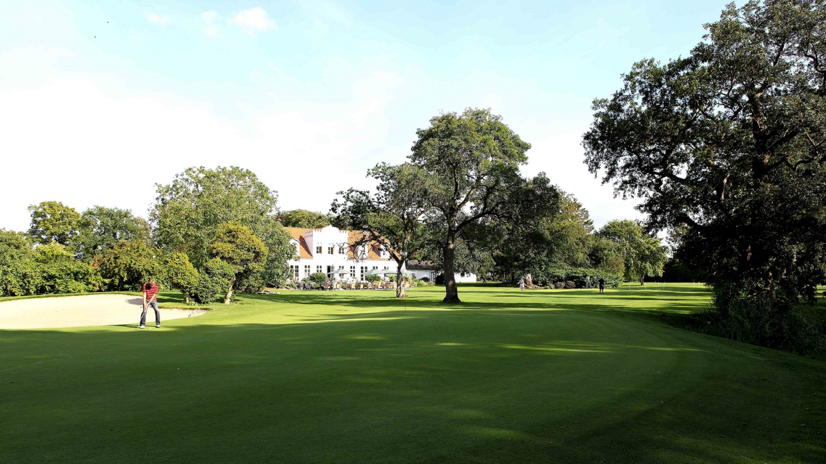 Barløseborg Golfklub, mand spiller golf på smuk grønt område med Barløseborg i baggrunden.